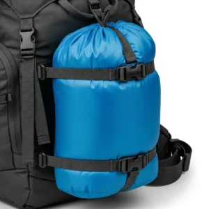 A packed sleeping bag stuff sack securely attached to the outside of a hiking backpack, showcasing portability and space-saving for campers.