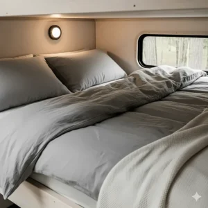 A minimalist and stylish bedding setup for an adult's camper bunk, featuring neutral colors and durable materials.