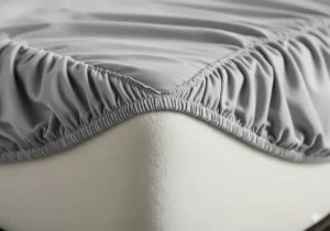 Close-up of an RV bunk fitted sheet's elasticized corner, showing the deep pockets designed to securely fit over a thick RV bunk mattress.