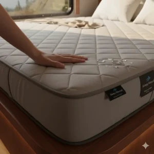 A hand touching a thick, easily removable, and waterproof camper mattress cover, demonstrating durability and easy cleaning.