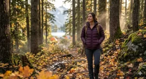 A woman wearing a slim-fit down jacket for camping while trekking through an autumn forest.