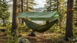 A waterproof rain tarp installed above a camping hammock to provide shelter during wet weather conditions.