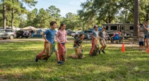 Kids playing a potato sack race on the grass at a campground