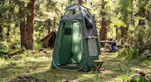 A camp shower tent rigged with a black solar water bag hanging from the top frame.