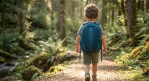 Rear view of a young boy carrying an ergonomic kids hiking backpack with padded shoulder straps.