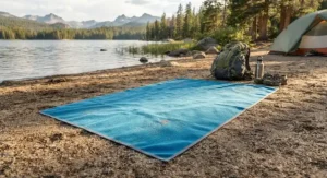 A sand-free microfiber towel for camping laid flat on sandy ground near a lake during a weekend camping trip.