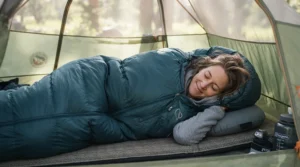 A tall hiker stretching out inside an elongated 3-season sleeping bag for side sleepers in a backcountry tent