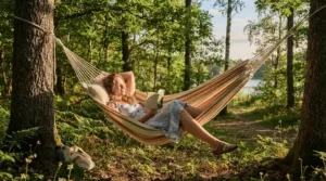 A camper lounging in a backyard hammock with a breathable budget summer sleeping bag on a warm afternoon.