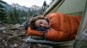A budget mummy sleeping bag with the draft collar and hood cinched tight against windy conditions