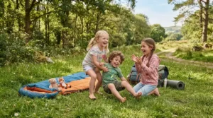 Happy children playing near a rectangular sleeping bag for family camping in a sunny campsite