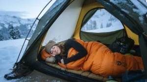 A woman camping in the snow using a winter sleeping bag for women designed for sub-freezing temperatures.
